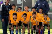 Young athletes posing for a team photograph with their instructors on the football field.