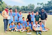Students posing with their trophy and medals after winning a football tournament.