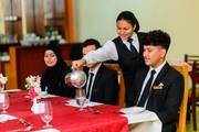 A hospitality student perfecting beverage service techniques during a hands-on practical session.