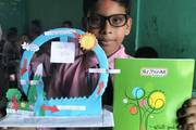 Grade 4 student showcasing a science project model of the water cycle.
