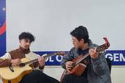 Students performing a guitar duet during an extracurricular activity.