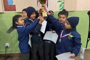 Young students celebrating their achievement in an inter-school futsal tournament.