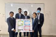 Second-year Health Assistant students presenting an educational wall chart on communicable diseases.